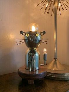 a cat lamp sitting on top of a wooden table next to a clock and candle holder