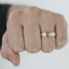 a person's hand with a gold wedding ring on it and a diamond in the middle