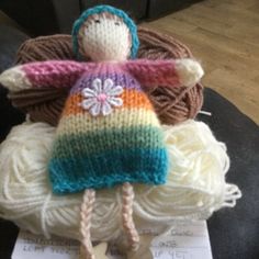 a knitted doll sitting on top of a pile of yarn