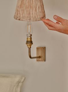 a lamp that is on the wall next to a person's hand