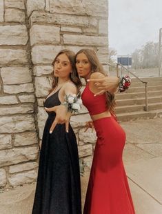 two beautiful young women standing next to each other in front of a stone wall and stairs