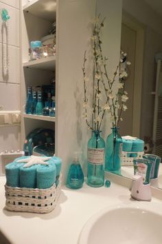 a bathroom sink with blue towels and vases on it