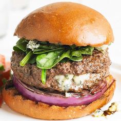 a hamburger with lettuce, tomato and cheese on it sitting on a plate