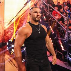 a man standing in front of a stage with people behind him and onlookers