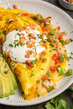 a white plate topped with an omelet covered in sour cream and toppings