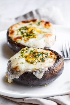 two stuffed mushrooms on a plate with a fork