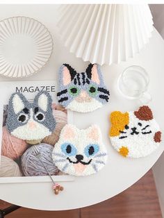 four crocheted cats are sitting on top of a table next to yarn balls