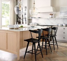 a kitchen with white cabinets and black chairs in front of an island that has marble counter tops