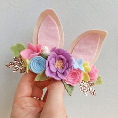 a hand holding a flower and bunny ears hair clip