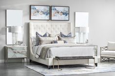 a white bed sitting in a bedroom next to two pictures on the wall above it