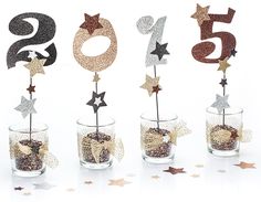 the numbers are placed in small glass vases with star decorations on top, along with chocolate balls and sprinkles