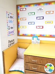 a room with yellow desks and colorful bulletin boards on the wall behind it,