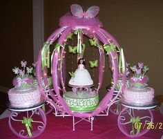 a wedding cake with butterflies on it and three cakes in the shape of a carriage