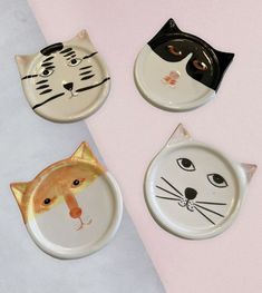 three plates with cats painted on them and one has a cat's head in the middle