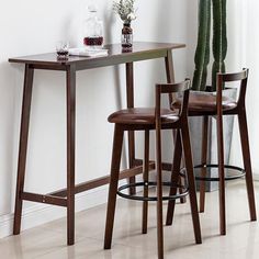 two stools and a table in front of a window with a potted plant