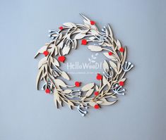 a paper wreath with red berries and leaves on the front is cut out to look like an ornament