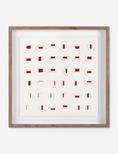 a white and brown framed artwork with red squares on the bottom, in a wooden frame