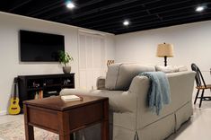 a living room filled with furniture and a flat screen tv mounted on the wall above it