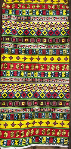 a colorful blanket hanging from the side of a wall next to a wooden frame with an ornate design on it