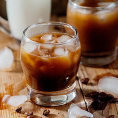 two glasses filled with ice sitting on top of a wooden table