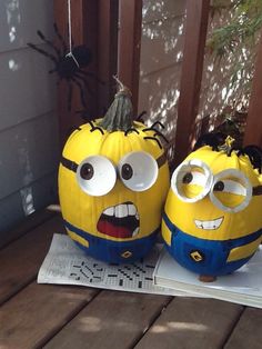 two yellow and blue pumpkins with googly eyes sitting on top of a table