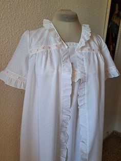 Vintage 70s by Fraulein white  nightgown and robe trimmed with lace, pink satin ribbon and ruffle in loose flowing silhouette. Marked size 10, missing composition label/ look cotton/. Very good condition. Measurement taken flat: Nightgown: armpit to armpit -  39 cm/15.4" length - 105 cm/41.2'' from top of shoulder Robe: shoulder to shoulder - 35 cm/13.8'' armpit to armpit - 50 cm/19.8'' sleeve length - 24 cm/ 9.5'' sleeve opening - 17 cm/6.6" diameter length - 109 cm/42.9'' White Ruffled Sleepwear, White Ruffled Dress For Home, Feminine Ruffled Nightgown For Wedding, White Lace Trim Sleepwear For Home, White Ruffled Nightgown For Wedding Night, Feminine Ruffled Wedding Nightgown, Vintage Ruffled Nightgown For Sleepovers, Feminine White Ruffled Sleepwear, Pink Ruffled Nightgown For Sleepover