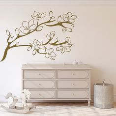 a baby's room with a dresser and wall decal in the shape of a tree