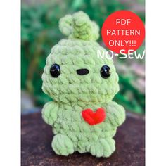 a small green stuffed animal with a red heart on it's chest sitting on a rock