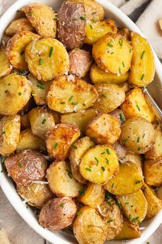 a white bowl filled with roasted potatoes and parsley