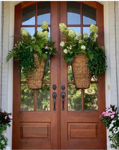 two baskets with flowers are on the front door