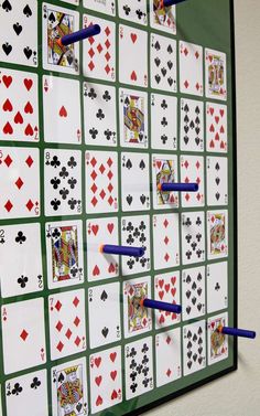 several playing cards are arranged on the wall with blue pegs in each hand and one is holding two pencils