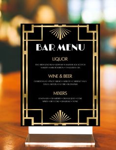 a black and gold art deco style menu card on a wooden table with a blurred background