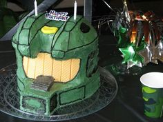 a green birthday cake sitting on top of a table next to a cup and fork