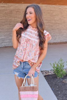 Level up your spring tops with this fun floral top in peachy orange! Pair it with denim shorts or white denim for an eye catching spring look. Floral high neck top Flowy fit Flutter sleeves Gorgeous pattern throughout Button closure up top in back Full coverage Runs true to size Also available in Sky Blue Piper is 5'3, wears a size 2 and is wearing a Small! Casual Flutter Sleeve Top For Spring, Trendy Summer Blouse With Flutter Sleeves, Spring Floral Print Tops With Flutter Sleeve, Casual Flutter Sleeve Blouse For Spring, Casual Spring Blouse With Flutter Sleeves, Summer Pink Flutter Sleeve Tops, Chic Peach Summer Tops, Peach Short Sleeve Summer Blouse, Summer Peach Tops For Day Out