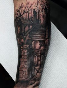 a man's arm with a black and grey tattoo on it, depicting stairs leading up to a cemetery