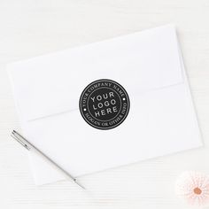 an envelope with a sticker that says your logo here on it next to a pen and flower