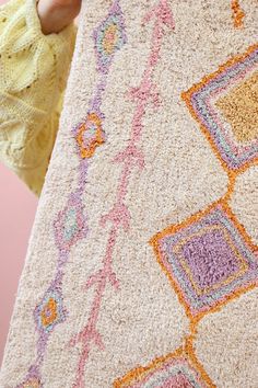 a person holding up a rug with colorful designs on it