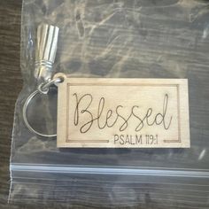 a wooden keychain with the word, blessed on it and a ribbon around it