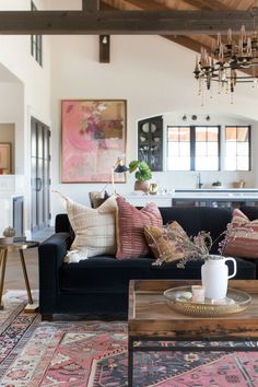 a living room filled with furniture and a chandelier hanging from the ceiling over a coffee table