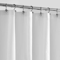 white curtains hanging on the side of a curtain rod in front of a gray wall