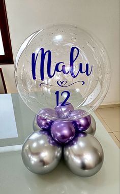 a clear glass ball with purple and silver ornaments on it that says, march 12