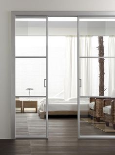 an open sliding glass door in a bedroom with white walls and wood flooring on the side