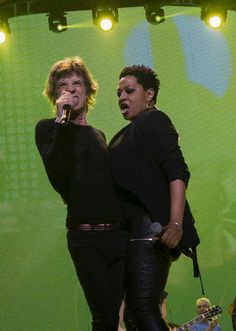 two women singing into microphones on stage