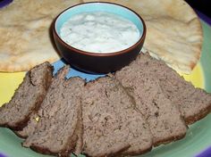 sliced meat and pita bread on a plate next to a bowl of yogurt