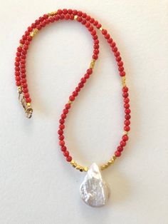 "Natural red coral beaded necklace featuring single creamy white Baroque pearl as the focal. Darling little gold vermeil faceted cubes add fun accents. Red coral gemstones are smooth 3mm rounds accented with solid 24k gold vermeil faceted cubes. Stunning focal is a large flat Baroque shaped cultured pearl in white with lovely iridescent sheen. Pearl is 17 x 22mm with total drop of 7/8\". Beaded necklace closes with 14k gold fill spring ring clasp and gold fill findings. Available in several leng Handmade Red Coral Pearl Necklace Gift, Gold Beaded Necklace With Polished Red Coral, Red Coral Beaded Round Necklace, Handmade Red Coral Pearl Necklace, Paris Charm Bracelet, Adjustable Hand-strung Red Coral Beaded Necklaces, Coral Beads Necklace, Red Coral Necklace, Baroque Pearl Necklace