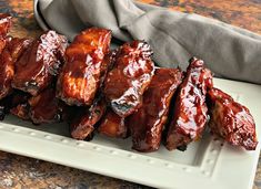 barbecue ribs on a white plate with sauce and napkins in the backgroung