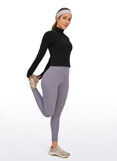 a woman in grey leggings and a black top is posing for the camera