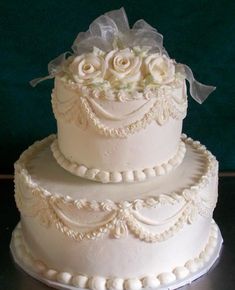 a three tiered wedding cake with white flowers on the top and ribbon at the bottom