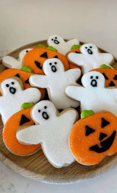 decorated cookies with ghost and pumpkin faces on a wooden platter, ready to be eaten