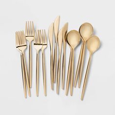 gold colored utensils are lined up on a white surface